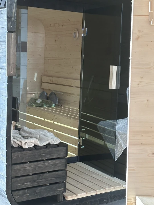 Innenraum der Qubik Lux Sauna – zentraler Blick auf Harvia Ofen und Massivholzbänke.